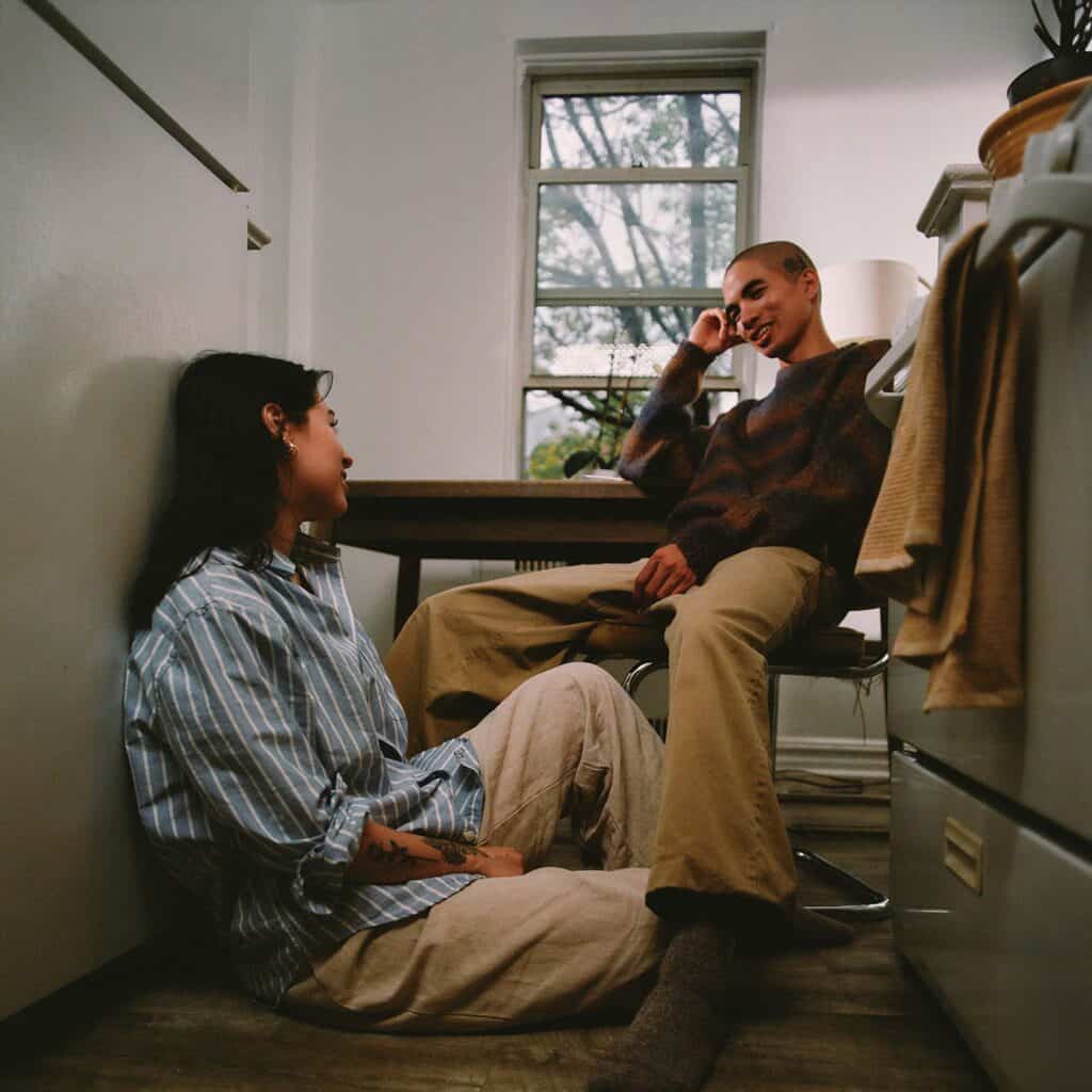 A husband and wife smiling and talking in the kitchen