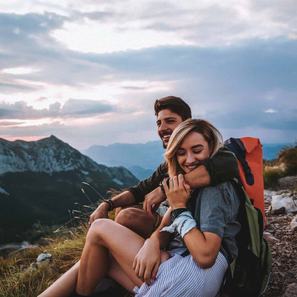 Married couple happy and hugging on a mountain after a hike.