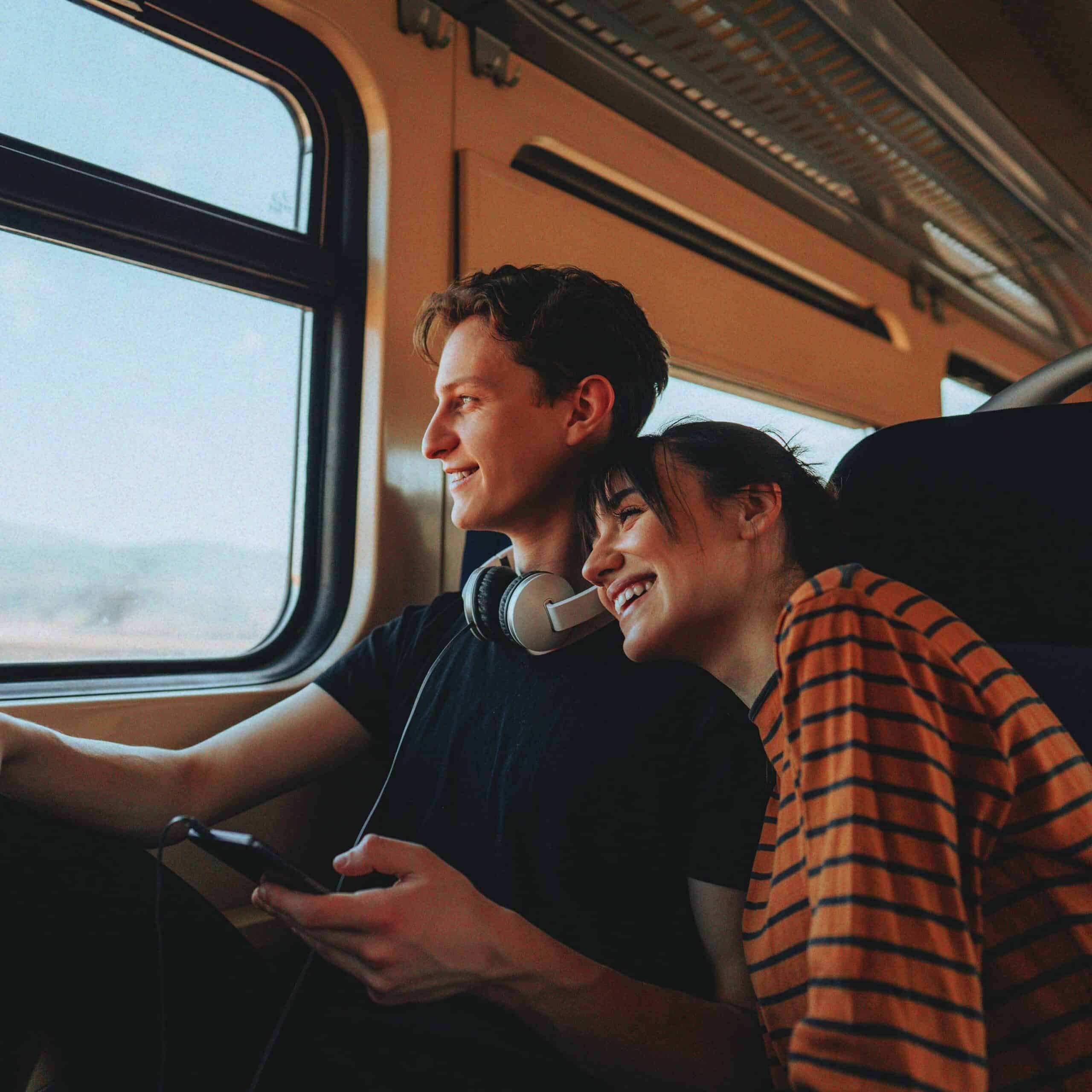 A husband and wife smiling while looking out the window while traveling on a bus together.