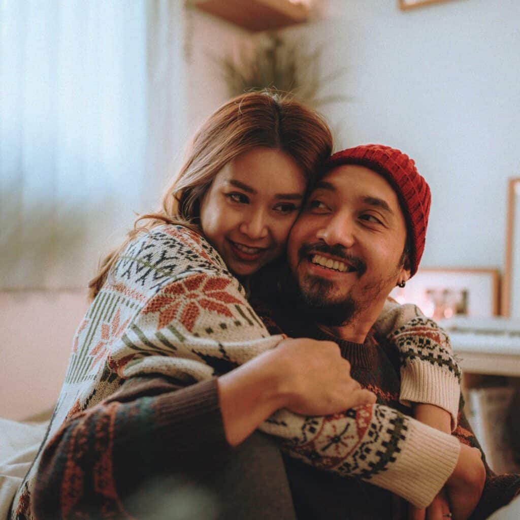 Woman wrapping her arms around her husband while they both smile.